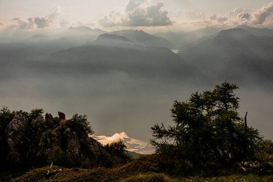 Mountain landscape exploration features misty peaks and glowing sunbeams with in the background the famous Garda Lake, Monte Baldo Natural Park, Brentonico, Trentino, Veneto, Italy.
