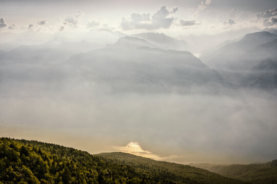 Mountain landscape with hazy mountain ridges and Garda lake view offers tourism exploration in nature at Monte Baldo Natural Park, Brentonico, Trentino, Veneto, Italy.