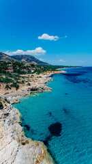 Obraz premium Drone aerial view of a rocky Mediterranean coastline with crystal clear turquoise sea, mountains, and secluded bays under a blue sky. Luxury travel, resort destination, summer vacation, coastal touris