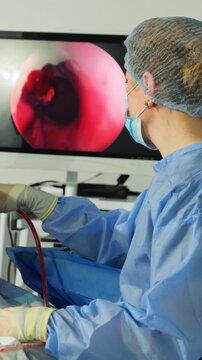 Doctor conducts endoscopic surgery displayed on medical monitor in room. Surgeon woman uses arthroscope for minimally invasive procedure vertical shot