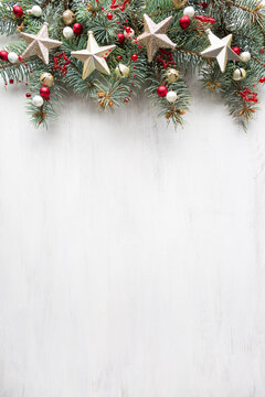 Fresh fir branches with Сhristmas ornaments  on old white wooden shabby background with empty space for text. Christmas and New Year background with holiday decorations. Flat lay.