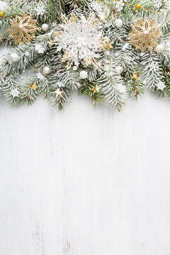 Spruce branch covered with snow and decorated with Christmas ornaments on old white wooden shabby board with empty space for text. Christmas and New Year background with holiday decorations. Flat lay