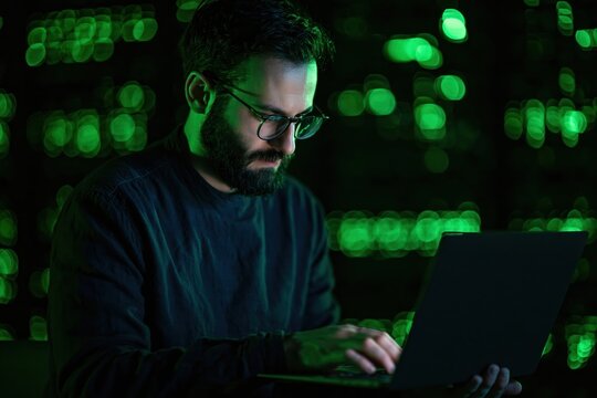 Programmer and developer coding software on a computer in a dark technology room