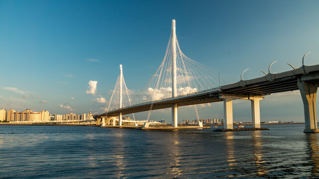 Modern cable-stayed bridge architecture at sunset with city skyline in the background. Western High-Speed Diameter over the Gulf of Finland. Cinematic look.