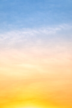 Sunset or sunrise sky with a vibrant gradient of orange, gold, and soft blue. Clear atmosphere with wispy clouds. Peaceful, natural light background. hope, freedom, new day Concepts, Vertical