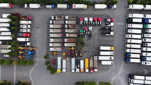 Aerial view of construction equipment and trucks parked in organized rows at an industrial site, showcasing various vehicles and machinery in a well-maintained lot