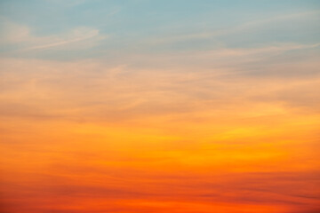 Obraz premium Beautiful sunrise sky with vibrant gradient orange and gold colors and soft blue, Clear atmosphere with wispy clouds. Peaceful, perfect for background and copy space, High resolution images
