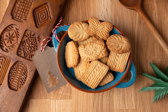 Homemade speculoos cookies in a bowl next to an old speculoos cookie cutter, baking delicious cookies yourself