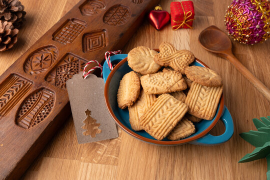 Homemade speculoos cookies in a bowl next to an old speculoos cookie cutter, baking delicious cookies yourself