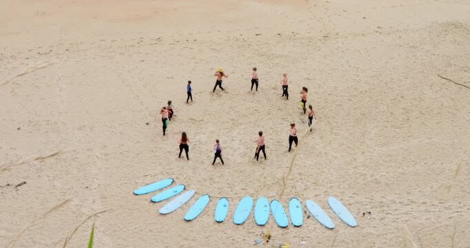 Circle of Surfers on the Sand: A group of surfers form a circle on a sandy beach, their surfboards laid out in a crescent shape.