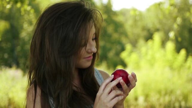 Close-up portrait of lovely dark-haired young woman holding her head in hands at summer green park.