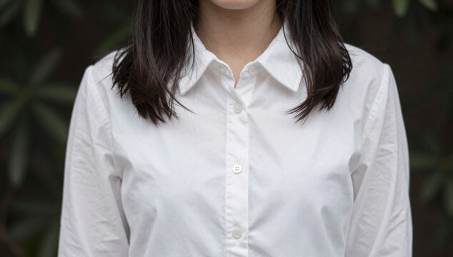 Close-up of a woman in a white collared shirt and dark hair with a blurred background