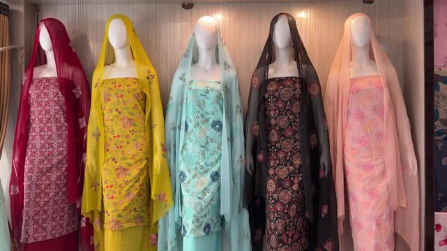 Shararas, ghararas, and straight suits displayed on rowed mannequins in a Pakistani boutique showroom.