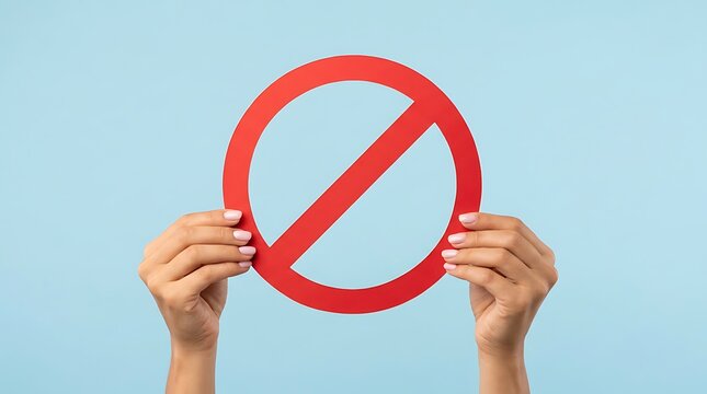 Person holding red prohibition symbol against light blue background signifying stop or forbidden.