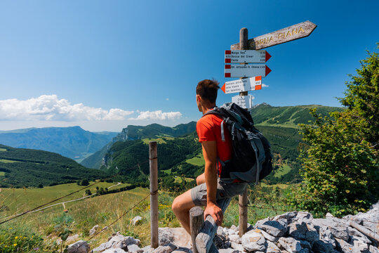 Vipere Equipped Trail, San Valentino di Brentonico.Hiker with backpack rests by a trail sign San Valentino di Brentonico, Monte Baldo Natural Park, Brentonico, Trentino, Italy.