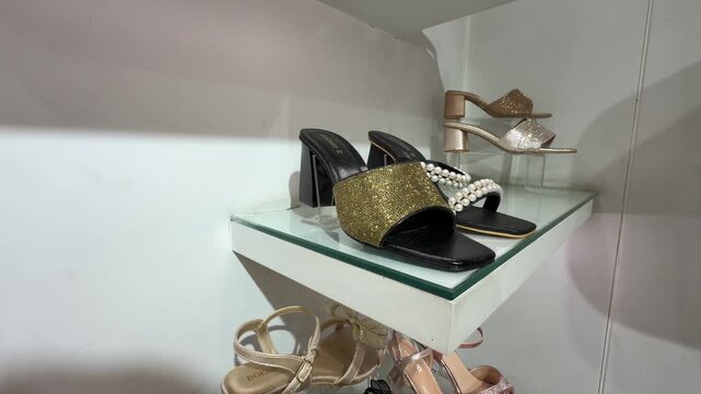A stylish retail footwear shelf showcasing a pair of embellished block‑heel mules with elegant decorative detailing.