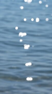 Sunlight glints on the rippling surface of calm blue water, creating a serene and tranquil visual experience.