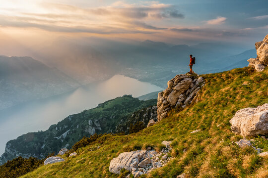 Adventure travel hiker stands on a cliff edge enjoying the sunset, Altissimo Refuge "Damiano Chiesa",Monte aldo Natural Park, Brentonico, Trentino, Veneto, Italy.