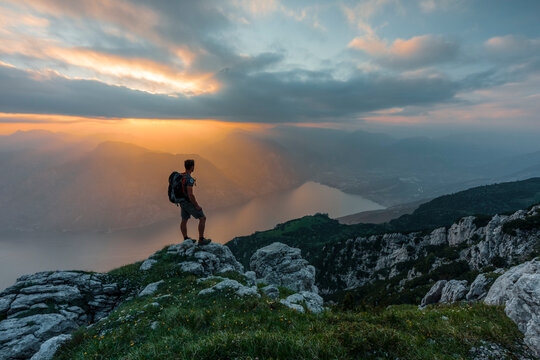 Adventure hiker stands on a mountain summit at sunset for exploration and travel, at Monte Baldo Natural Park, Altissimo Refuge "Damiano Chiesa", Brentonico, Trentino, Veneto, Italy.
