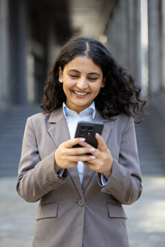 Woman smiling and texting on smartphone outdoors in city