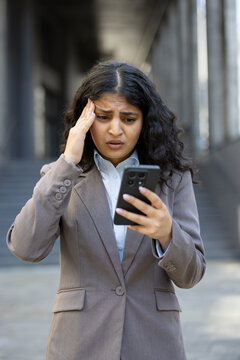 Businesswoman experiencing headache from distressing news on phone