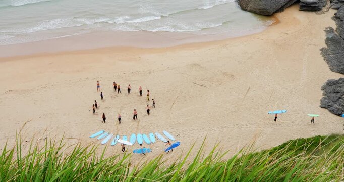Surf's Up: A group of surfers with their surfboards arranged on the sand are gathered for a lesson or meeting on a beautiful beach.