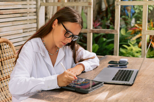 Woman checking smartphone while working with laptop at outdoor workspace