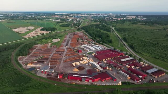 Aerial view of large timber processing facility with railway and Ventspils Port at sunrise in Latvia