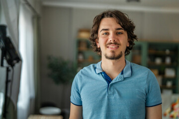 Fototapeta premium Smiling young man wearing blue polo shirt indoors