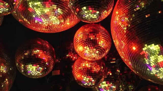 Countless mirrored disco balls reflect a mesmerizing dance of shifting warm and cool light from above, creating a dazzling atmosphere in a vibrant nightlife venue.