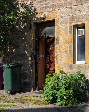 Forres stone dwelling with an open wooden front door, revealing a glimpse of the interior during a bright day in Moray, Scotland