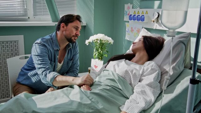 Hopeful husband holds hand of sleeping wife high-risk patient