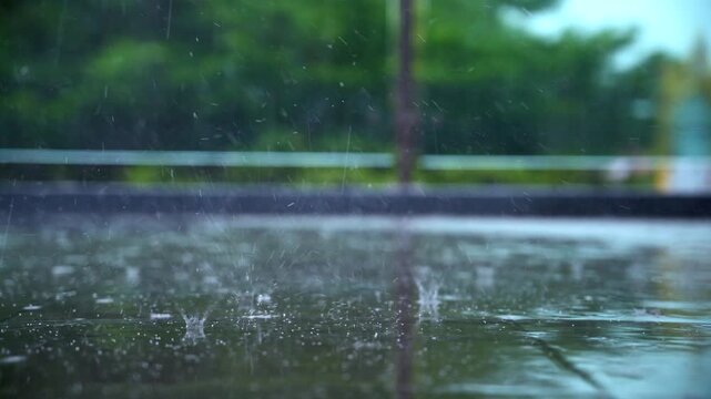 Slow motion close up of raindrops splashing on wet ground during a tropical storm