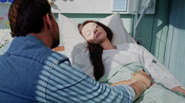 Woman with disease sleeps in bed as husband sits nearby in ward
