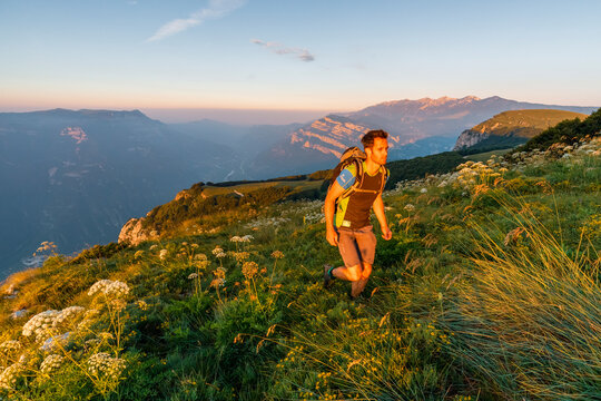 Male hiker walks through a mountain meadow at sunset for an outdoor adventure lifestyle, Vignola mount-Corno della Paura,Monte Baldo Natural Park, Brentonico, Trentino, Veneto, Italy.