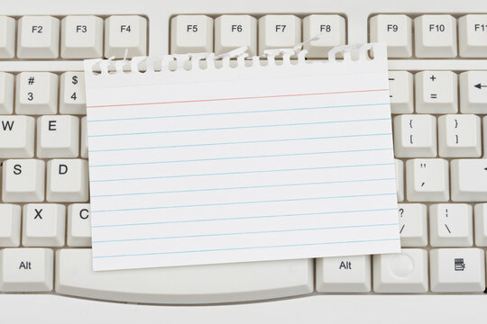 Blank ripped lined paper on a white computer keyboard for online education