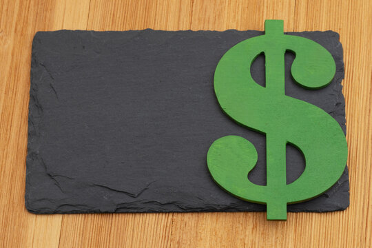 Blank chalkboard with green dollar sign on a wood desk