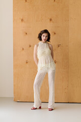 Fototapeta premium Elegant brunette model in chic white lace outfit showcases modern fashion style