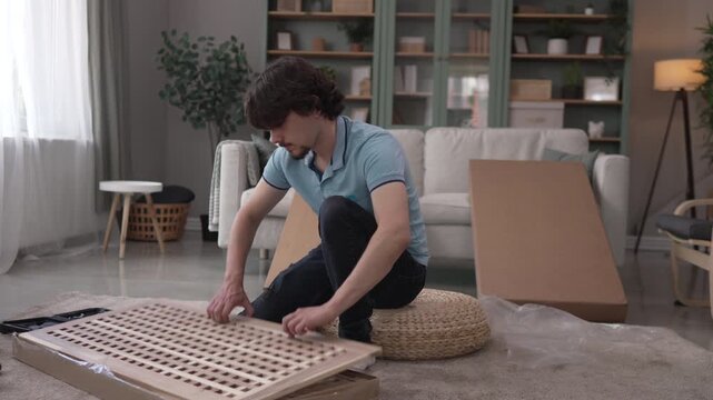 Man assembling flat pack furniture in his living room