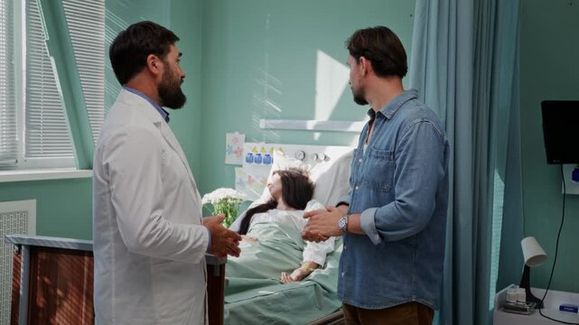 Bearded doctor discusses treatment with male visitor near bedside
