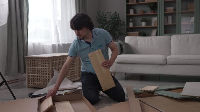 Young man unpacking and assembling new furniture