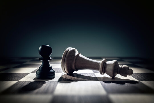 Pawn chess piece standing over defeated king concept for success, winning, confidence, ambition, aspirations and overcoming adversity