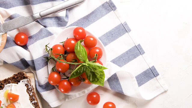 Fresh cherry tomatoes with green basil on a striped kitchen towel