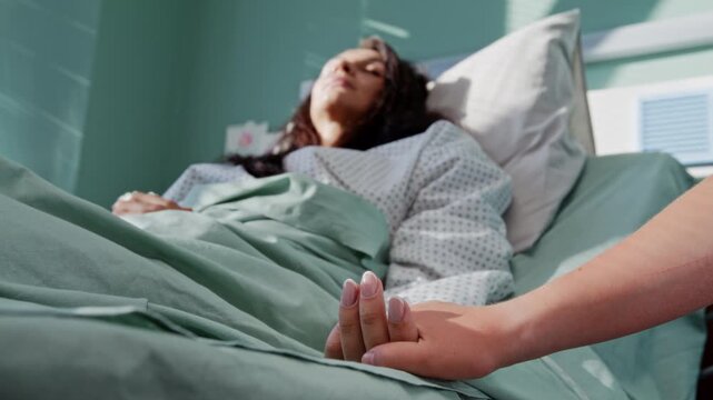 Girl comforts mother through gentle hand touch in hospital ward