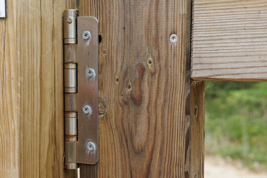 Metal hinge connecting two wooden fence panels outdoors