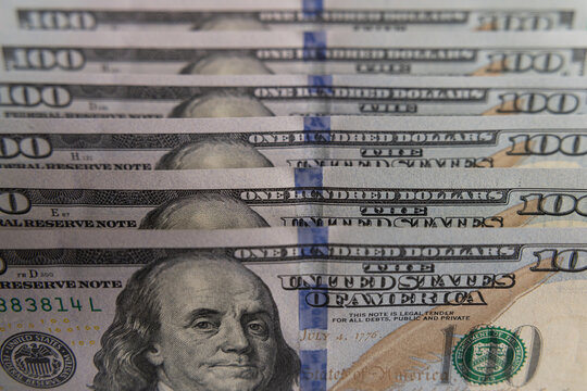 Close-up of US one hundred dollar bills stacked in diagonal rows with selective focus
