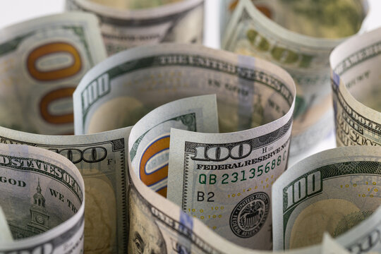 Close-up of scattered US one hundred dollar bills with selective focus on Benjamin Franklin portrait
