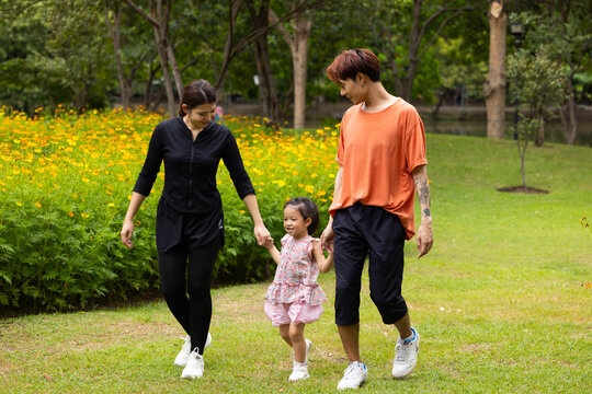 Mother and daughter walking hand in hand at spring park, moment of family bonding and togetherness. outdoor activitie. Asian Family with father mother daughter and grandfather