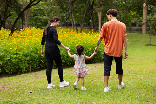 Mother and daughter walking hand in hand at spring park, moment of family bonding and togetherness. outdoor activitie. Asian Family with father mother daughter and grandfather