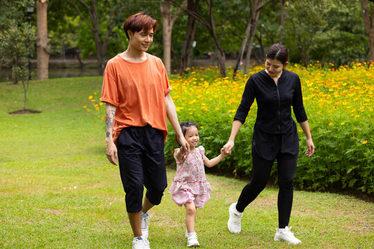 Mother and daughter walking hand in hand at spring park, moment of family bonding and togetherness. outdoor activitie. Asian Family with father mother daughter and grandfather